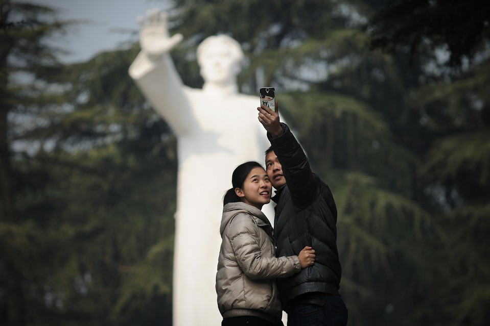 Молодая пара фотографируется на фоне статуи Мао Цзэдуна в его родном городе Шаошань провинции Хунань. Тысячи людей посетили Шаошань, чтобы почтить память "великого кормчего"