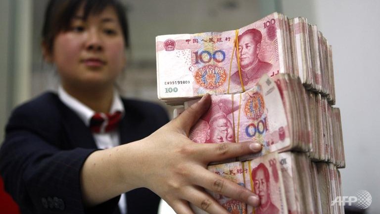 Кассир укладывает стопки юаней в Банке Китая