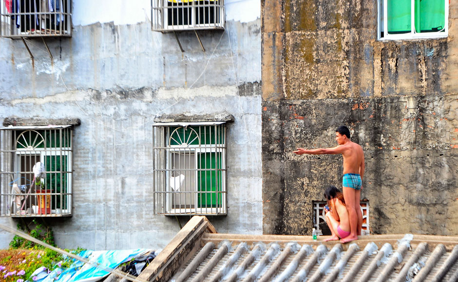 Мужчина стоит на крыше дома в Санья (Хайнань) и держит в заложницах свою девушку, угрожая ножом.Таким образом он пытался добиться от двух семей разрешения на их брак. Так продолжалось несколько часов, в конце концов мужчина был задержан полицией. Фото: Reuters/Stringer