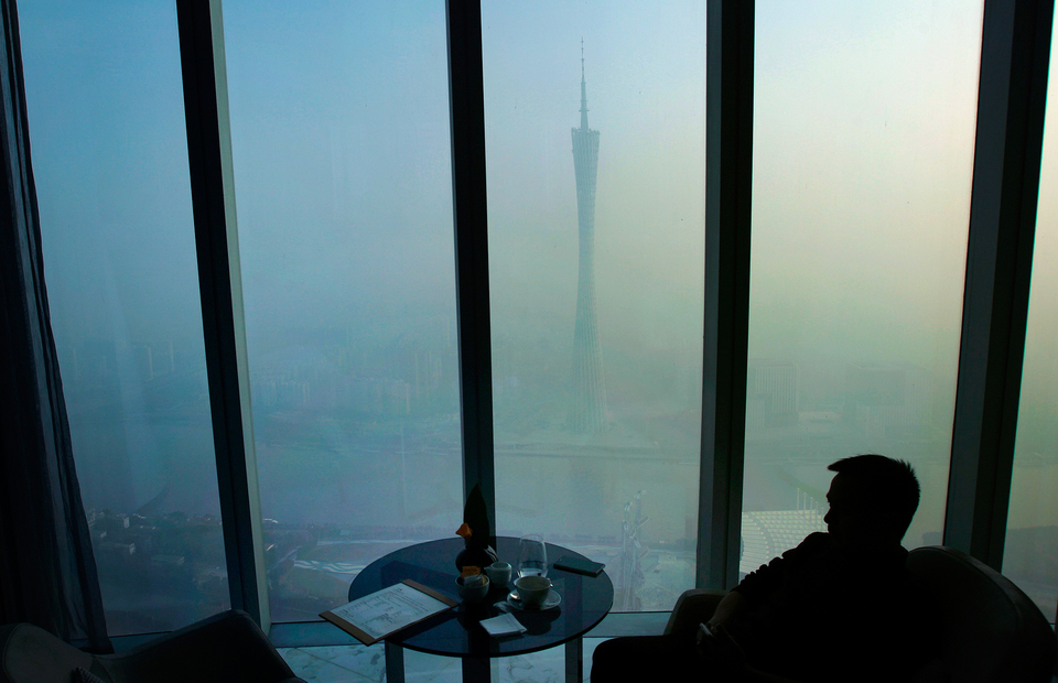Мужчина пьет кофе в ресторане на 70-ом этаже небоскрёба IFC в городе Гуанчжоу. По центру телевизионная башня, окутанная рекордным по плотности смогом. ИКВ (индекс качества воздуха) на днях превысил 300 пунктов, что считается критически опасным для здоровья. 