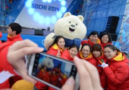 Члены олимпийской сборной Китая позируют на фоне талисмана зимних Олимпийских игр в Сочи.