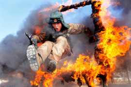 Солдат прыгает через огненное препятствие во время учений Народно-освободительной армии Китая в Хейхэ.