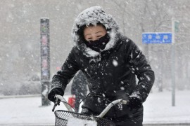 Женщина едет на велосипеде во время снегопада в городе Цицикар, провинция Хэйлунцзян.