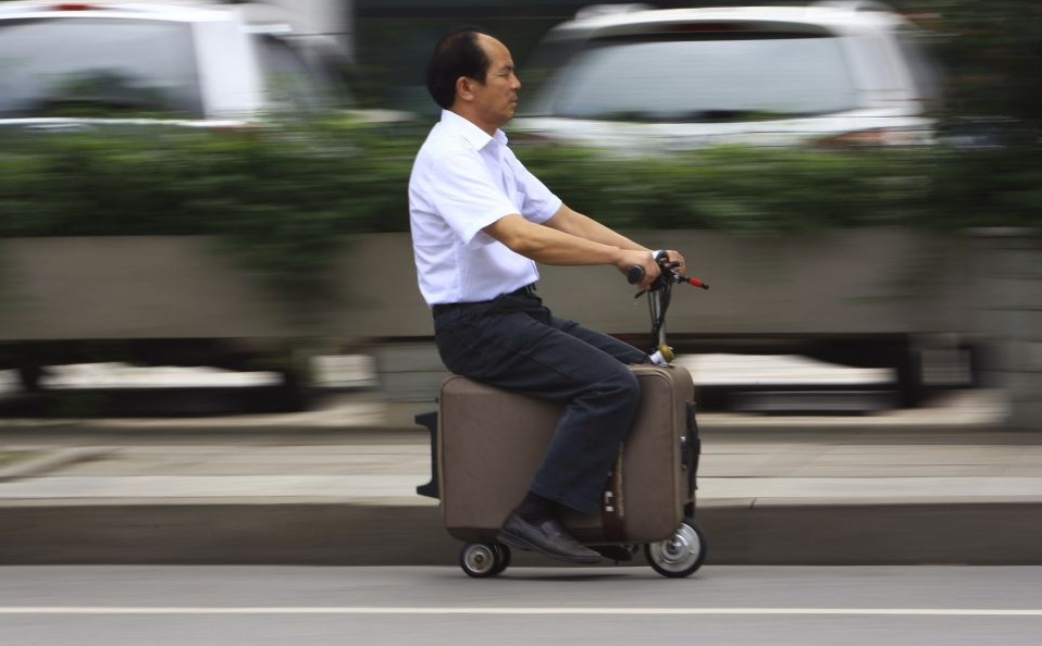 Хэ Лян на своем самодельном чемодане-мопеде на улицах города Чанша, на создание которого у него ушло 10 последних лет. Необычно средство передвижения развивает скорость 20 км/ч и весит 7 кг.