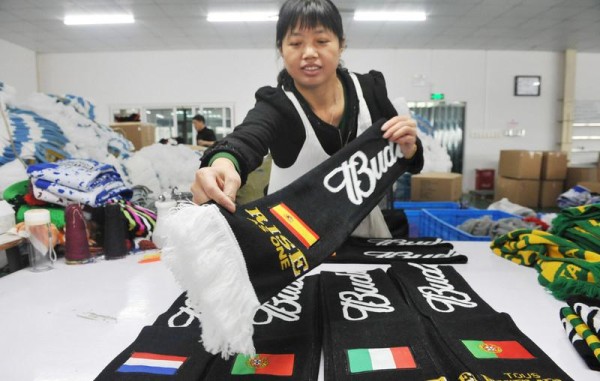 Работница китайской фабрики проверяет качество шарфов, изготовленных к ЧМ-2014