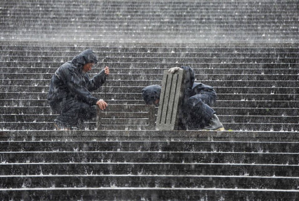 Рабочие во время ливня пытаются прочистить канализацию около Национального центра исполнительских искусств в Пекине. На этой неделе на китайскую столицу обрушились сильнейшие в этом году дожди.