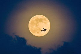 Самолет на фоне Луны в небе над Шэньчжэнем. Ночью в воскресенье жители Земли могли наблюдать самую большую Луну в 2014 году.