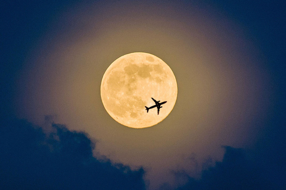 Самолет на фоне Луны в небе над Шэньчжэнем. Ночью в воскресенье жители Земли могли наблюдать самую большую Луну в 2014 году. 