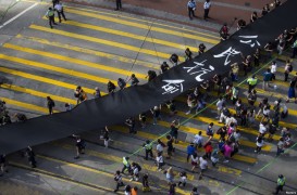 Участники движения за демократизацию Гонконга — Occupy Central (Оккупируй Централ) во время воскресного шествия с 500-метровым черным полотном, которое, по их словам, символизирует их протест против отказа Пекина разрешить прямые демократические выборы следующего главы администрации города