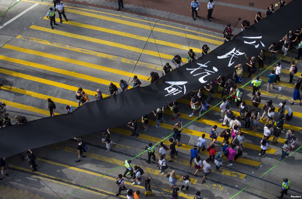Участники движения за демократизацию Гонконга — Occupy Central (Оккупируй Централ) во время воскресного шествия с 500-метровым черным полотном, которое, по их словам, символизирует их протест против отказа Пекина разрешить прямые демократические выборы следующего главы администрации города