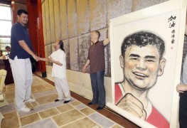 Бывший игрок NBA Яо Мин жмет руку художнику, который подарил спортсмену его портрет перед благотворительной игрой, которую организовал Фонд Яо, Дунгуань, провинция Гуандун.