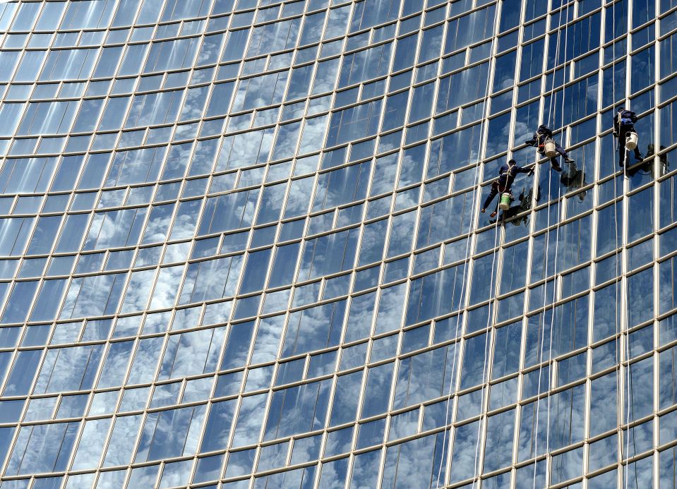 Рабочие моют стекла одного из офисных зданий в Пекине. 