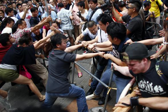 Сторонники Пекина (слева) пытаются снести баррикады активистов движения «Occupy Central»