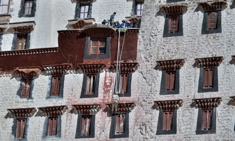 Рабочие красят стены дворца Потала в Лхасе, Тибет.