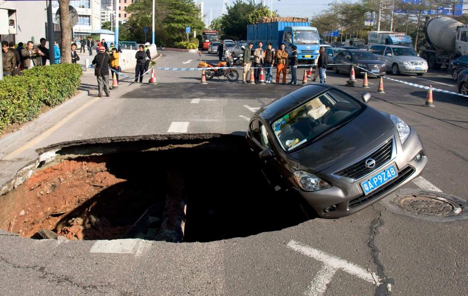 Машина, едва не провалившаяся, в неожиданно образовавшуюся яму на проезжей части, Гуанчжоу, провинция Гуандун. 