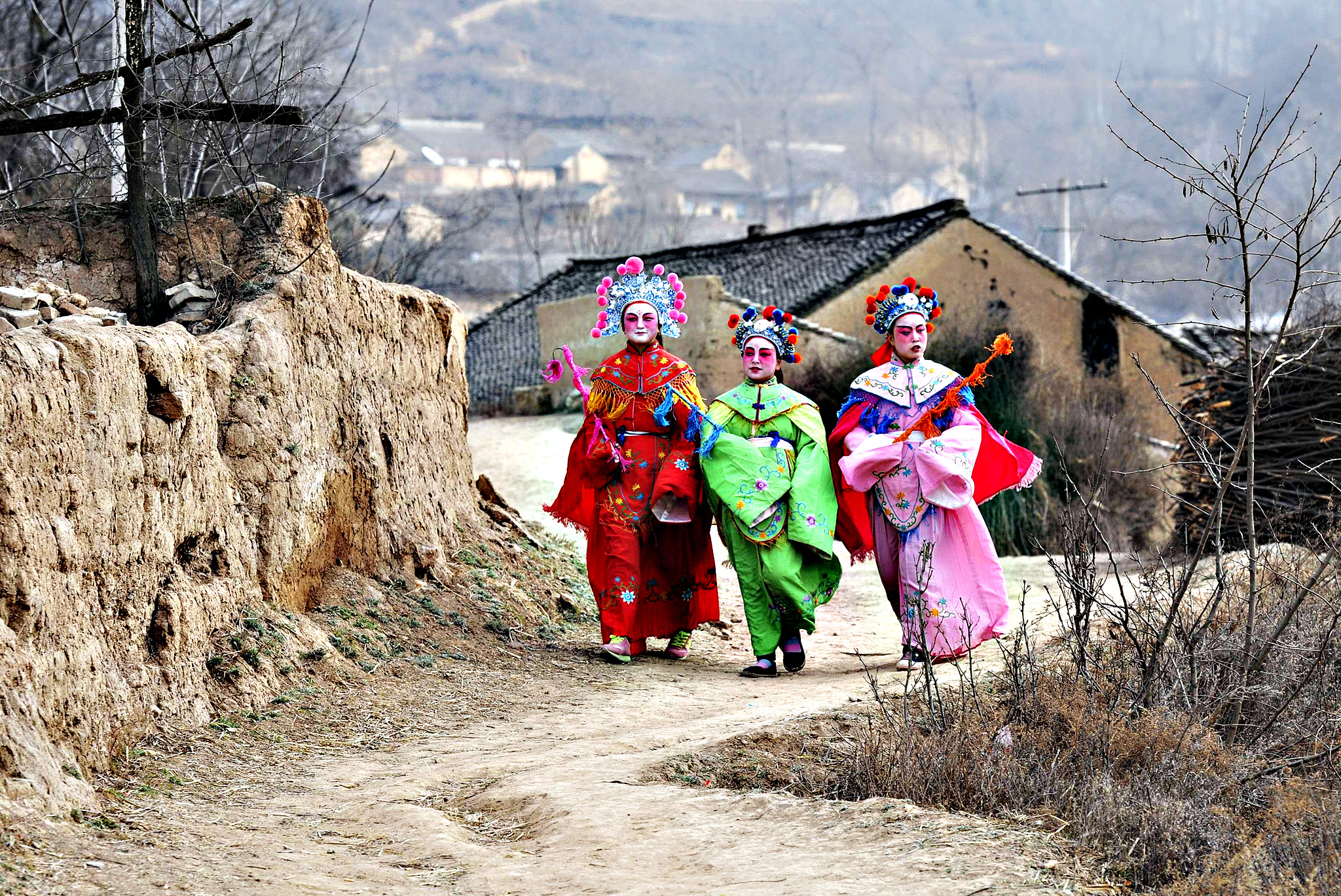 Девочки в традиционных костюмах гуляют перед выступлением на китайский Новый год в деревне Лунсянь провинции Шэньси