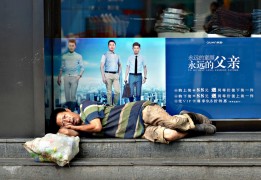 Бездомный отдыхает перед витриной магазина одежды в городе Хэфэй, провинция Аньхой.