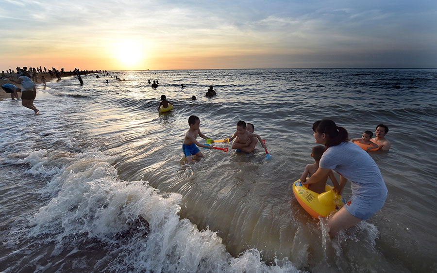 Люди купаются в море на городском пляже Хайкоу (о. Хайнань). На неделе температура воздуха в городе достигла +37 °С