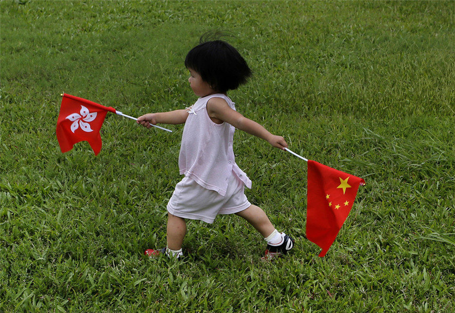 Девочка с флагами Гонконга и КНР на дне открытия военной базы НОАК в Гонконге.