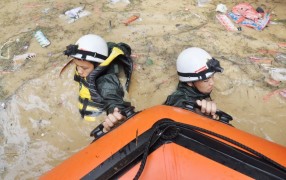 Спасатели тянут лодку в потоке грязной воды в уезде Сунтао провинции Гуйчжоу. На прошлой неделе ливни вызвали наводнения на Юго-Западе Китая.