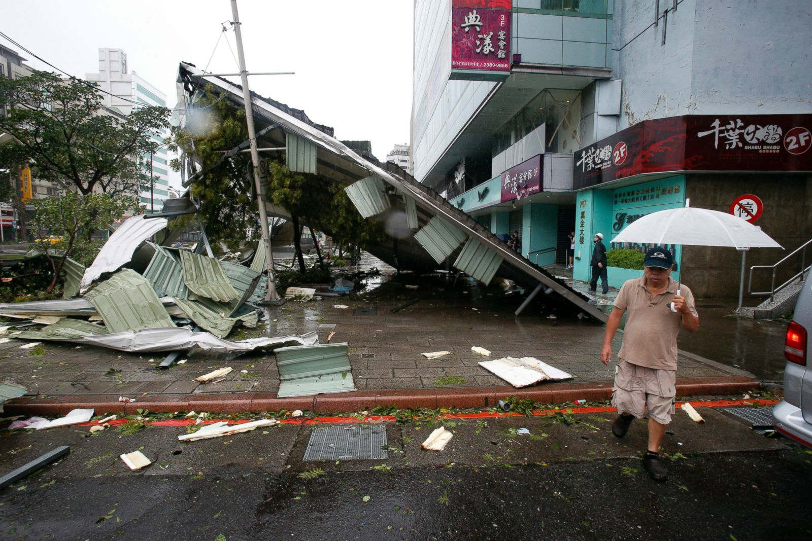 Человек идет рядом с сооружением, разрушенным тайфуном «Суделор».  Тайбэй. Фото