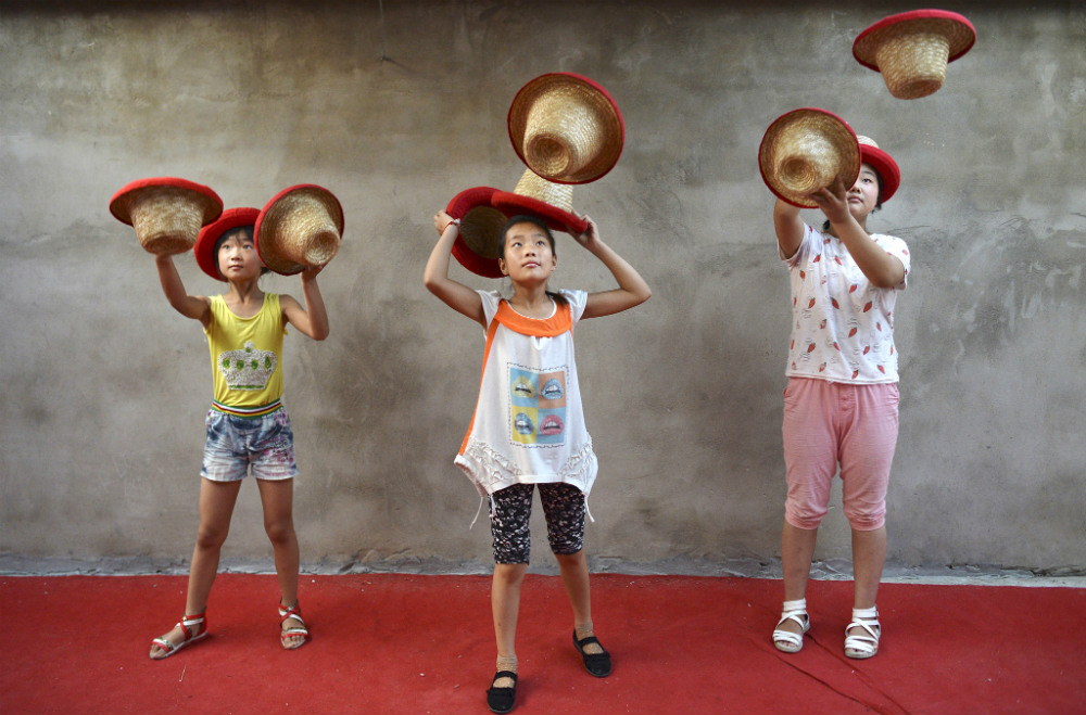 Ученицы акробатической школы в провинции Аньхой учатся жонглировать шляпами. Занятия начинаются в 4 утра и продолжаются в среднем 10 часов. 