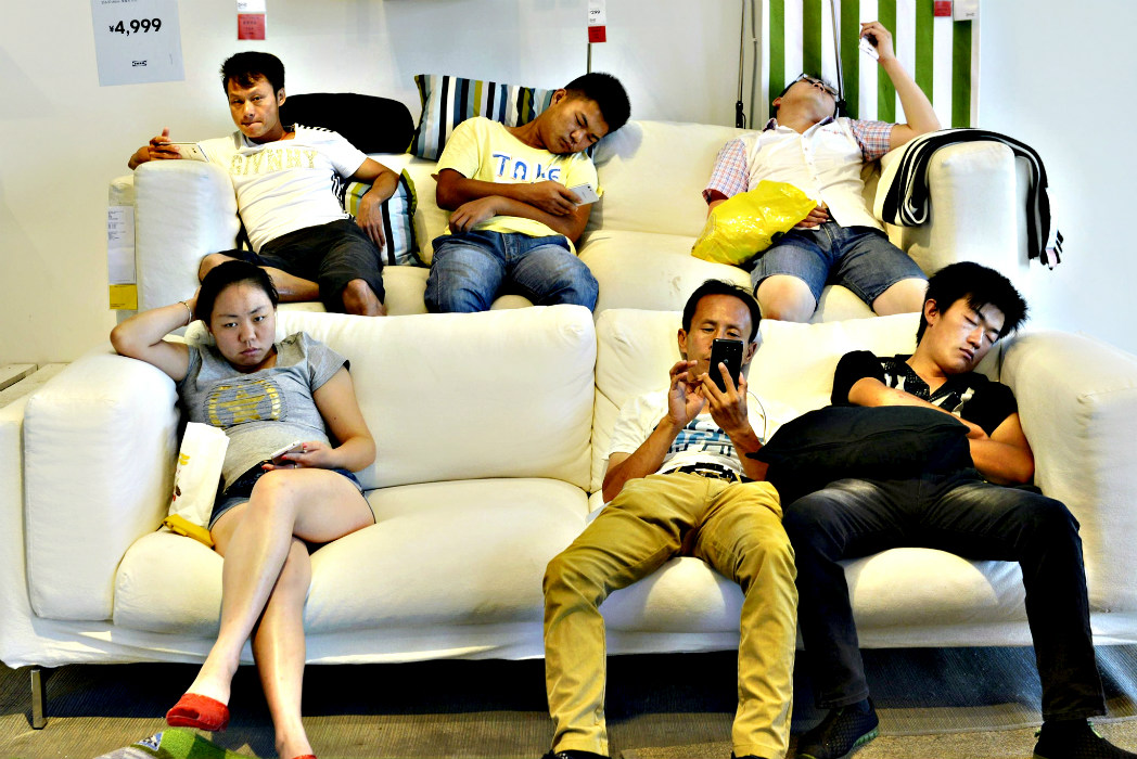 Посетители магазина ИКЕА в городе Ханчжоу отдыхают на диванах в демонстрационном зале. 