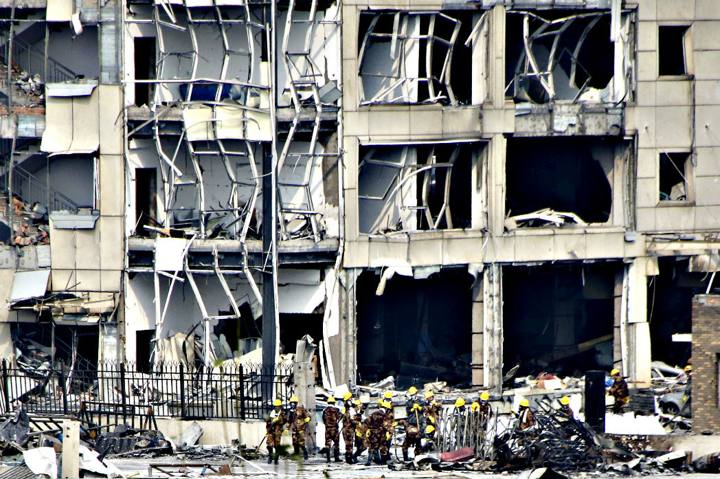 работает перед зданием в Тяньцзине, разрушенным взрывом 12 августа. 