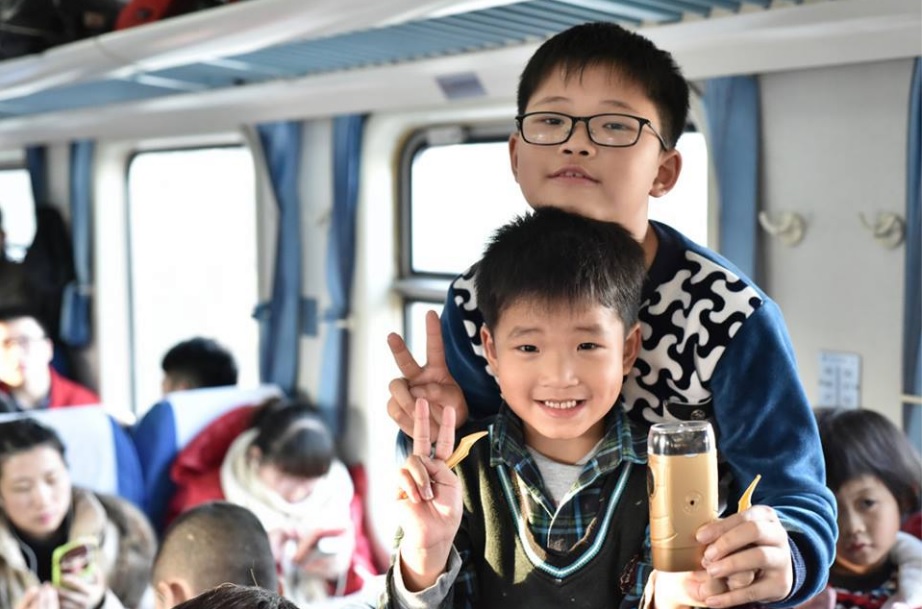 Пассажиры поезда Гуанчжоу—Чэнду, девятилетний Ван Цзяхуэй и шестилетний Ван Цзяжуй показывают электробритву, которую везут в подарок дедушке на китайский Новый год .