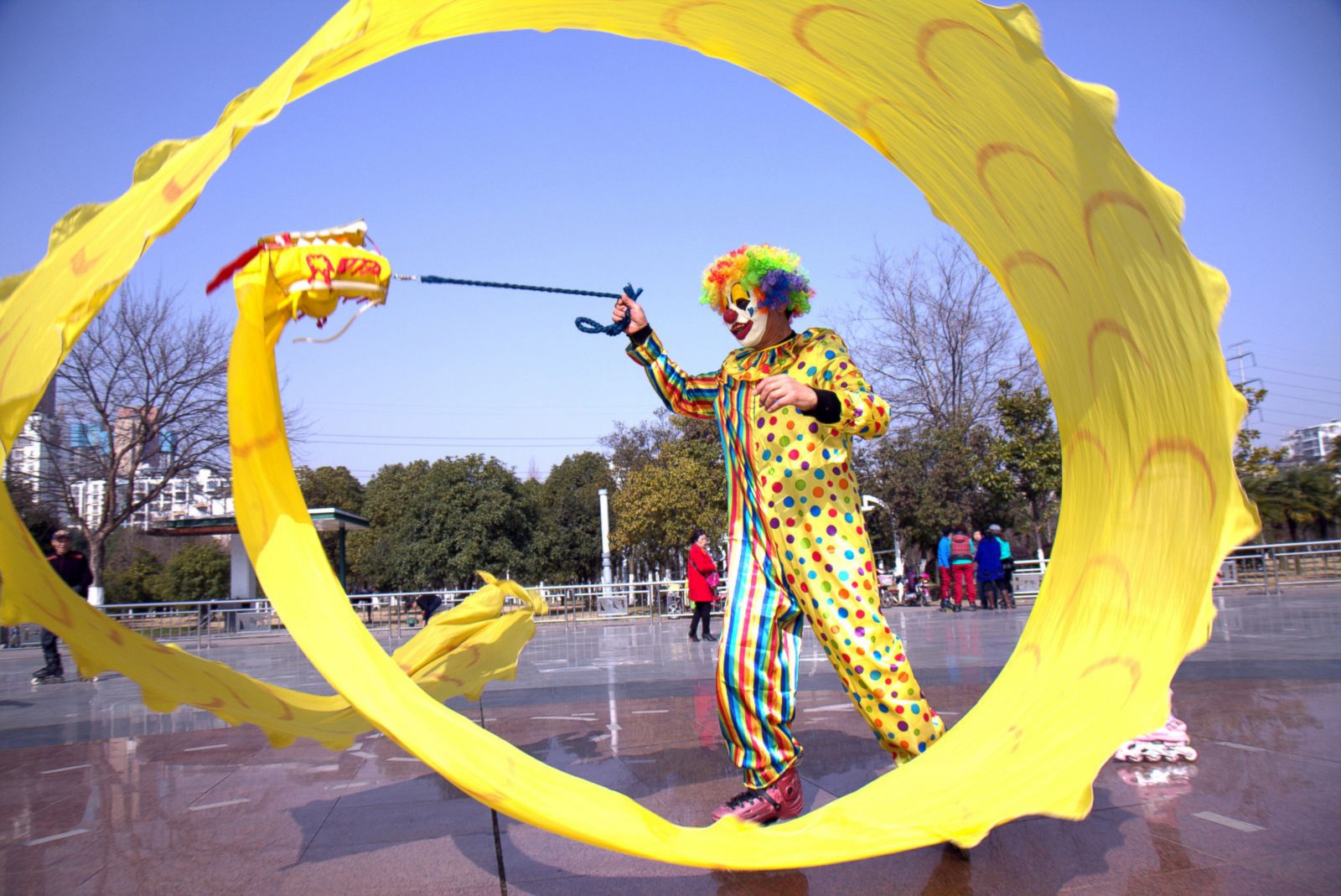 Клоун на роликовых коньках играет с тряпичным драконом в городе Ухань.