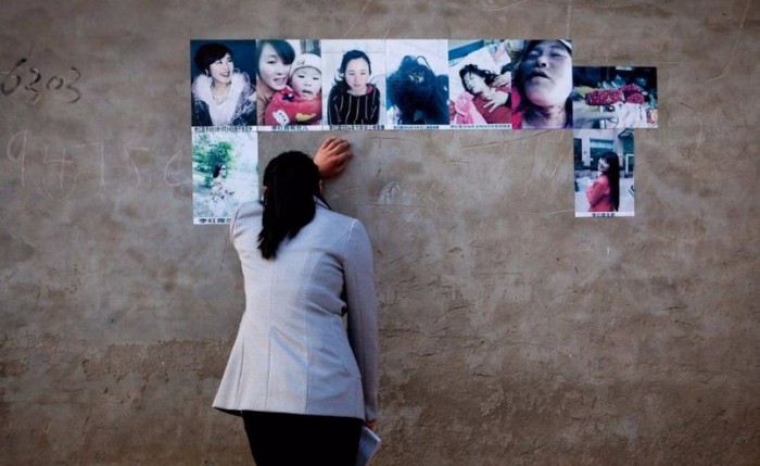 Сестра Ли Хунся плачет над фотографиями погибшей, развешанными на стенах дома, где она жила. Фото: washingtonpost.com