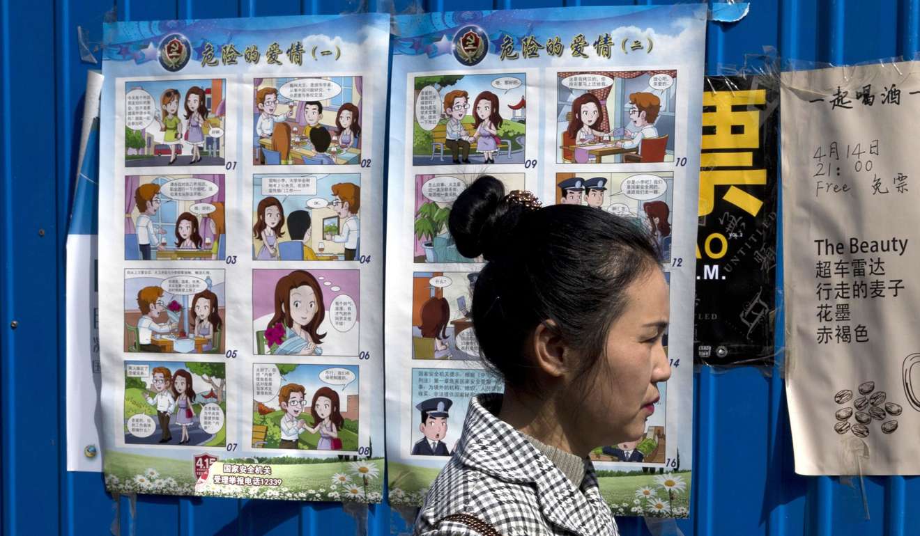 Девушка на фоне плакатов, призывающих к осторожности при общении с иностранцами. Фото: AP