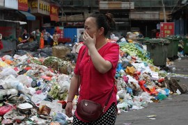 Пешеход прикрывает нос на заполненной мусором улице Баоань, Шэньчжэнь.