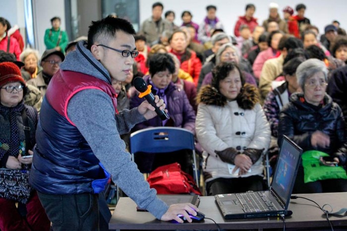 Волонтер объясняет пожилым людям, как пользоваться телефоном. Фото: Zhang Cunli/VCG