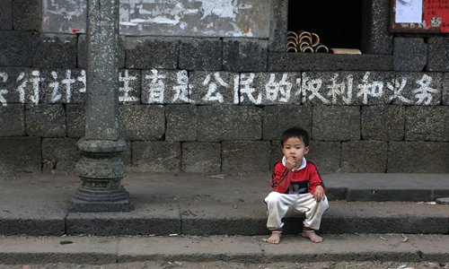 Ребенок сидит перед слоганом о семье. Фото: CFP