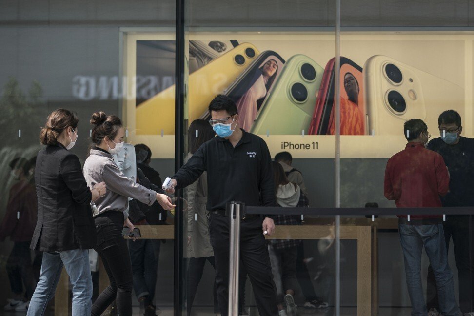 Сотрудник измеряет клиентам температуру на входе в магазин Apple