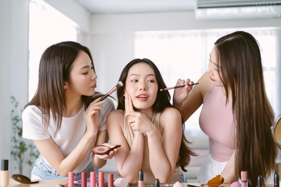 638822928026367935Two_girls_doing_the_makeup_of_a_girl_in_the_middle_of_them._.jpg